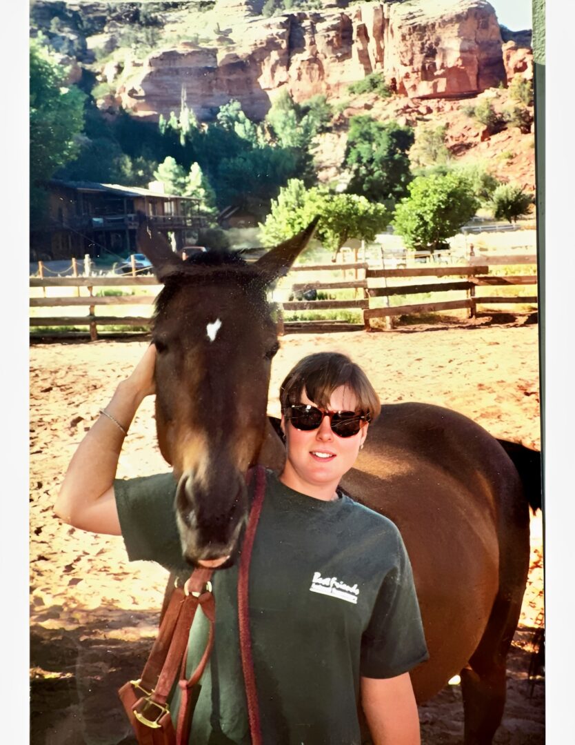Person smiling beside horse at desert ranch