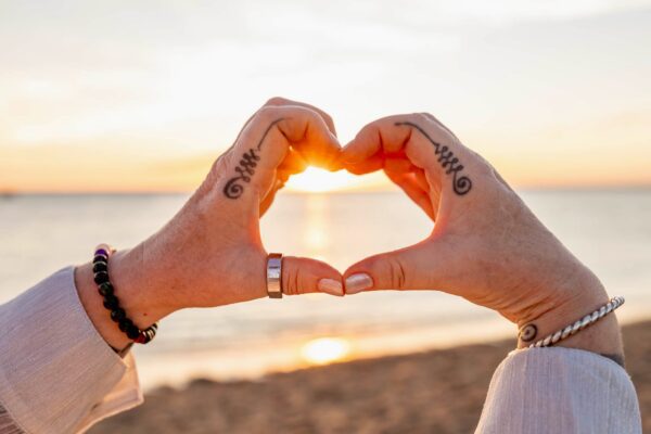 Tattooed hands framing sun in heart